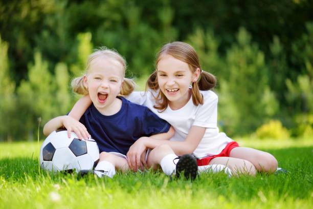 istock Two cute little sisters having fun playing a soccer game 980127280