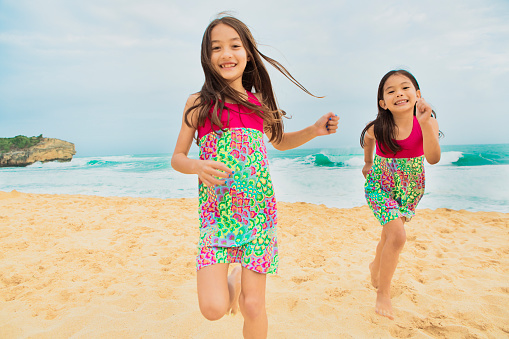 Hawaiian children playing and jumping on the beach. Photographed on the island of Kauai Hawaii.