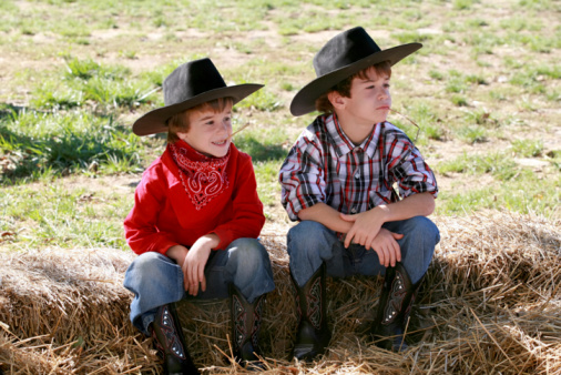 Two Young Cowboys Sitting on Hay Bales