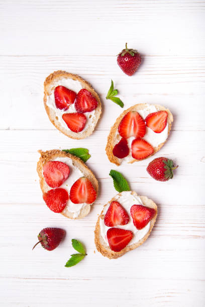 istock Toasts or bruschetta with strawberries on cream cheese on white background. 980167602