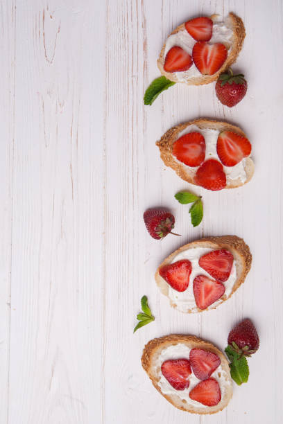 istock Toasts or bruschetta with strawberries on cream cheese on white background. 980176084