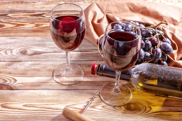 istock Red wine and red grapes on a wooden background. 980186066
