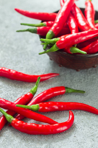 istock Red hot pepper pods close-up on a light background in a ceramic bowl 980186790