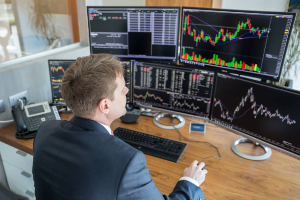 istock Stock trader looking at computer screens in trdading office. 980192084
