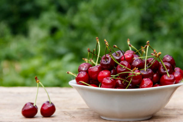 istock Bowl with fresh cherry on rustic wooden table outdoor 980196290