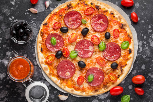 istock Italian pizza on thin dough with tomato sauce, salami, cheese, olives and Basil 980197098