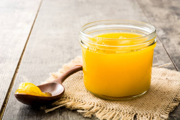 Ghee or clarified butter in jar Ghee or clarified butter in jar and wooden spoon on wooden table ghee stock pictures, royalty-free photos & images