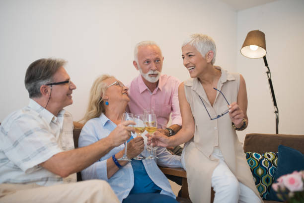 istock Two happy mature couples drinking wine at home 980219872