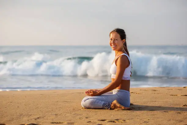 Photo of Caucasian woman practicing yoga at seashore of tropic ocean