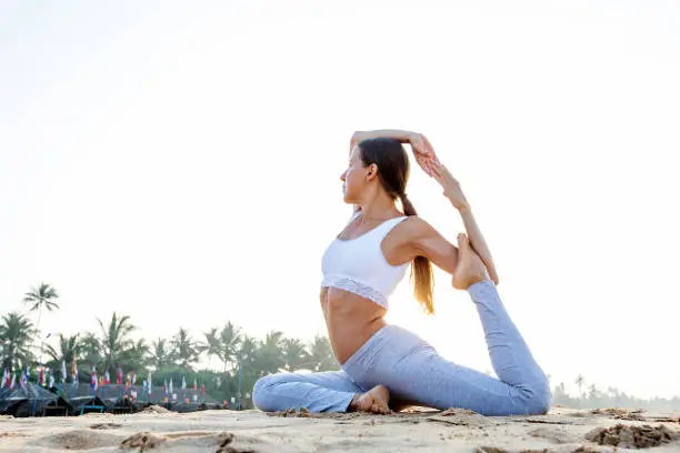 Photo of Caucasian woman practicing yoga at seashore of tropic ocean