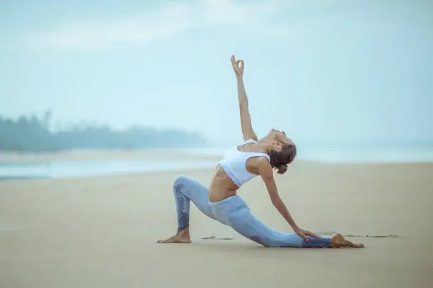 Photo of Caucasian woman practicing yoga at seashore of tropic ocean