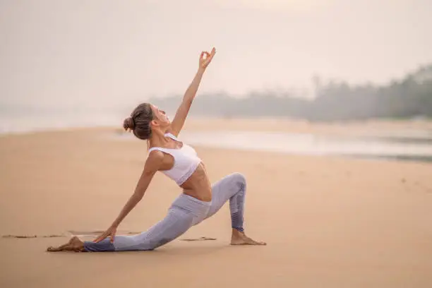 Photo of Caucasian woman practicing yoga at seashore of tropic ocean