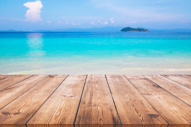 istock Wood table with blue sea and sand beach background 980233354