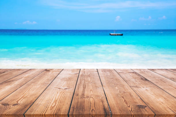 istock Wood table with blue sea and sand beach background 980233400