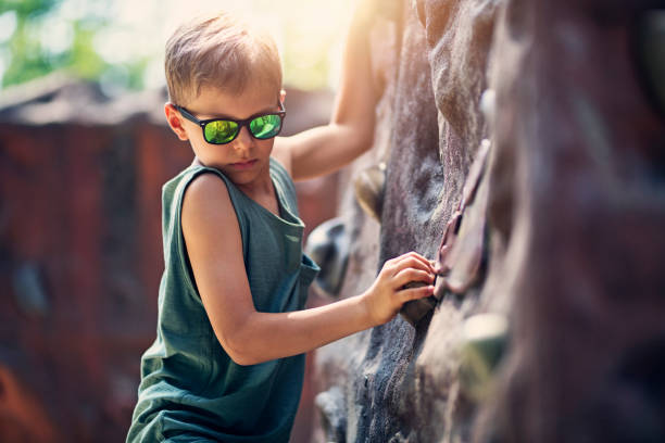 Little boy climbing on the outdoors climbing wall\nNikon D850