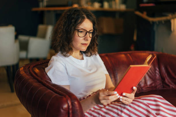 istock Young woman reading at home 980252444