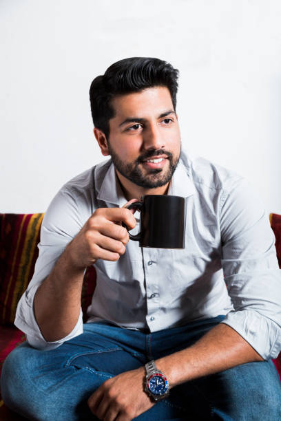 istock Smiling man sit on sofa and drink cup of coffee 980269054