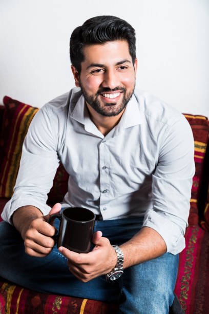 istock Smiling man sit on sofa and drink cup of coffee 980269056