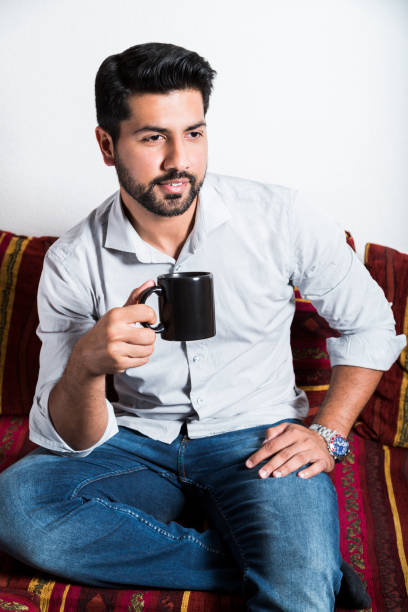 istock Smiling man sit on sofa and drink cup of coffee 980269058
