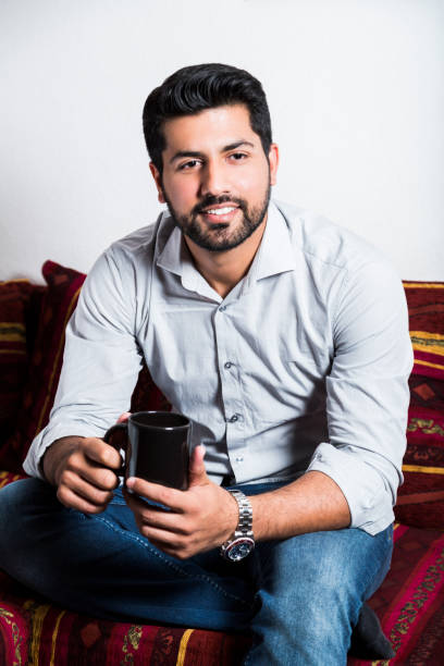 istock Smiling man sit on sofa and drink cup of coffee 980269070