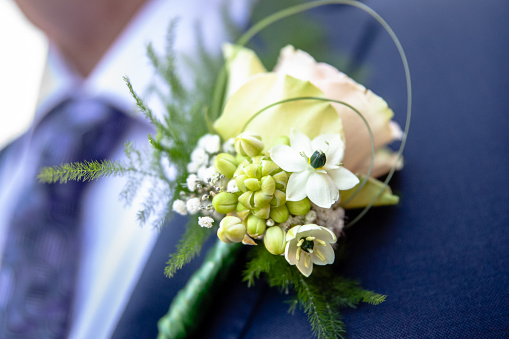 Cheerfully made up corsage with bright flowers. Groom with floral ornament for a wedding. Traditional wedding details for bride, brides sum and guests