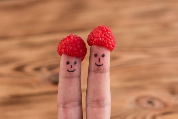 istock Two smiling faces drawn on fingers in caps from raspberry 980272924