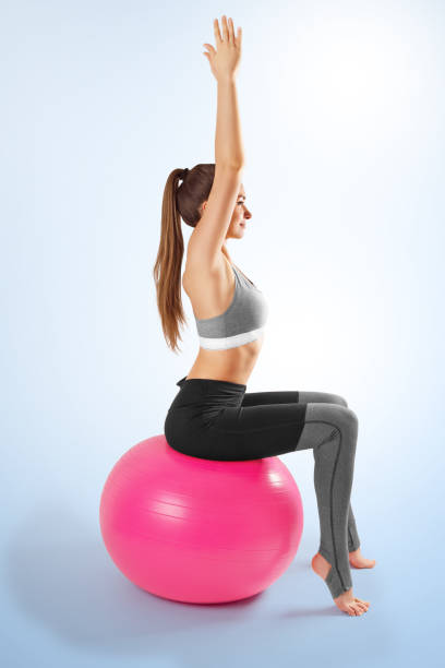Pilates and fitness sport girl in yoga fitness exercise on the floor, indoor training sitting on the pink pilates ball. Healthy lifestyle. Yoga position stock photo