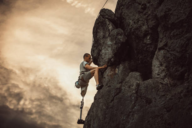Disabled Man Rock Climbing Man with prosthetic leg free mountain climbing. disabled person hiking outdoors stock pictures, royalty-free photos & images