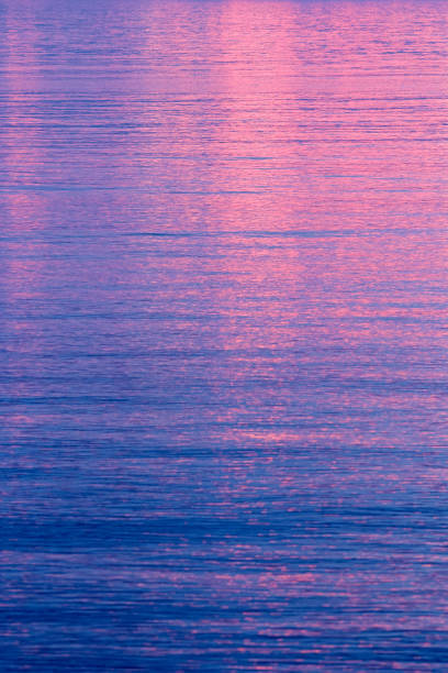 istock Vivid pink sunset reflected on calm water 980303768
