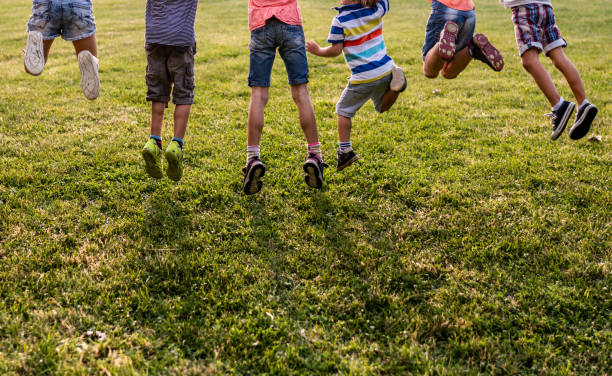istock Back view group of unrecognizable kids jumping in park 980304070