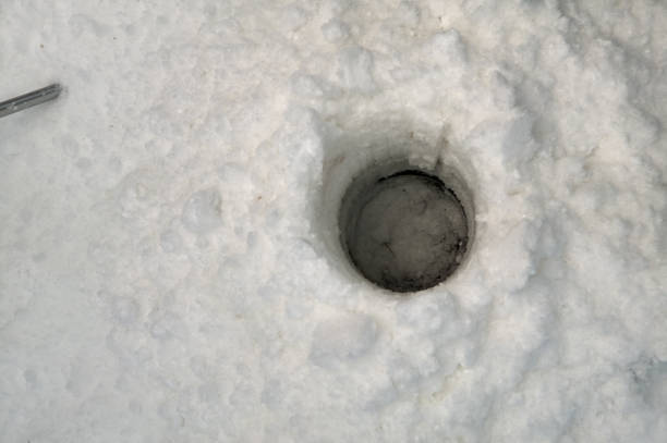 Circular hole drilled through the ice for fishing stock photo