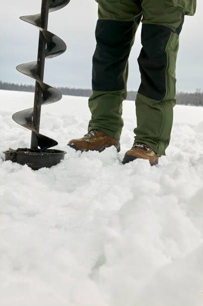 istock Man drilling hole in ice with large drill 980304602