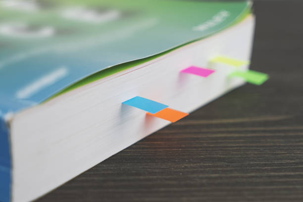 istock Edge of thick book with colored bookmarks on wooden table 980307246