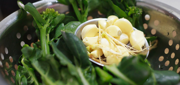 selective focus on food ingredient, garlic in vegetable metal colander or cullender