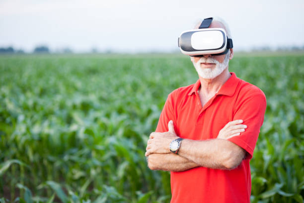 senior agronomist or farmer standing in corn field and using vr goggles - photography gray hair farmer professional occupation imagens e fotografias de stock
