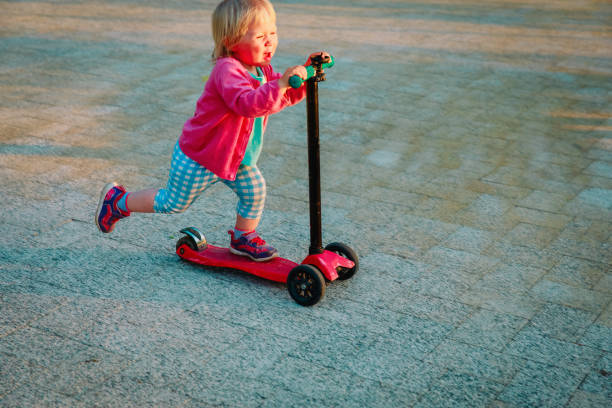 istock little girl riding scooter outdoors, active kids 980333460