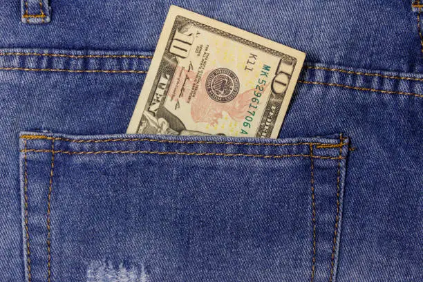 Photo of Ten dollars banknote in the pocket of blue jeans