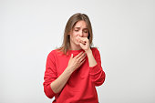 unhappy caucasian woman in red pulover suffering from throat pain at home