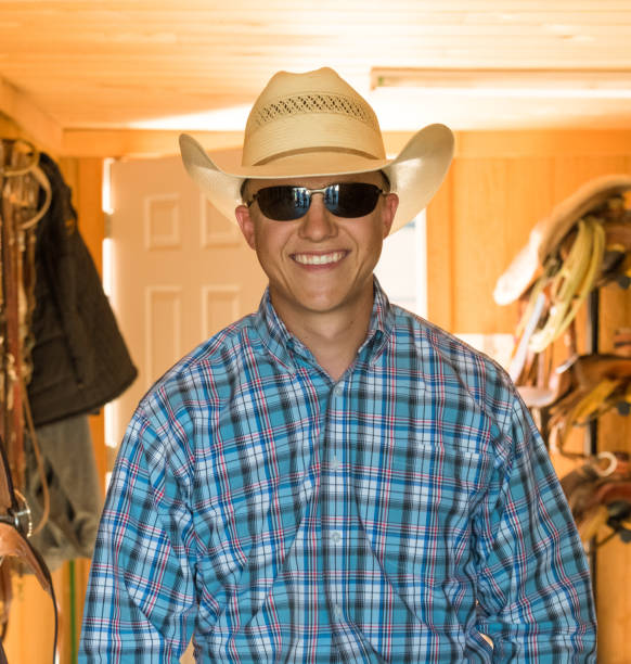istock Young cowboy and his equipment, saddles etc, smiling 980374482