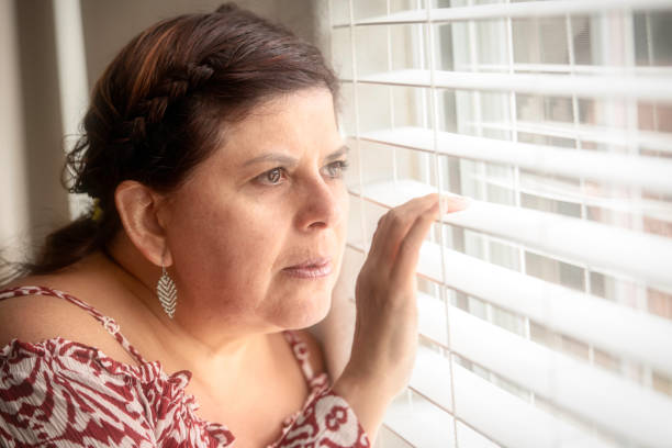 istock Smiling mature woman looking through a window 980386568