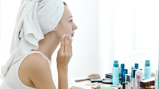 Young woman removing makeup from her face