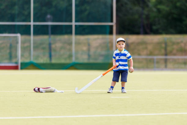 Small funny boy playing field hockey with stick. Concept field hockey image with copy space