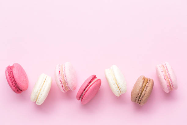 istock Colorful cake macaron or macaroon isolated over pastel pink background. Top view 980416826