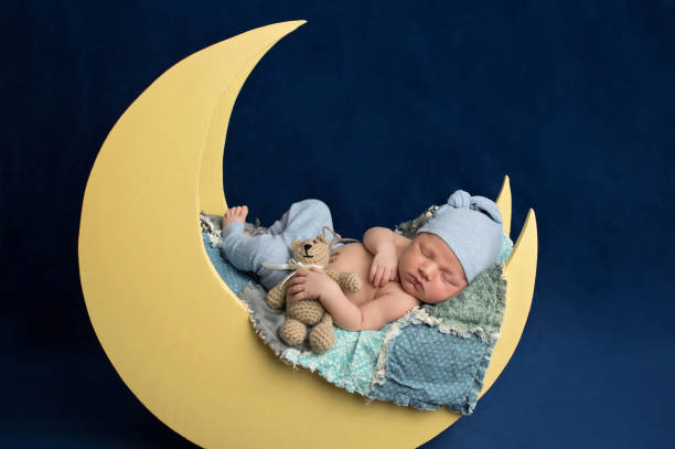 Newborn Boy Sleeping on the Moon with Teddy Bear stock photo