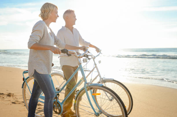 istock Mature couple walking their bicycles along the beach. 980422166