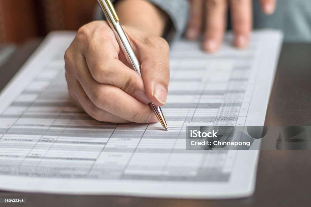 Administrator's hand fill in business schedule form document writing on yearly work plan, monthly timetable sheet, or weekly time table paper for office tasks, things and jobs to do list Education Registration Event Stock Photo