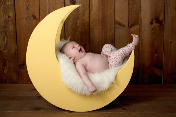 Baby Girl Lying on a Moon Shaped Photo Prop stock photo