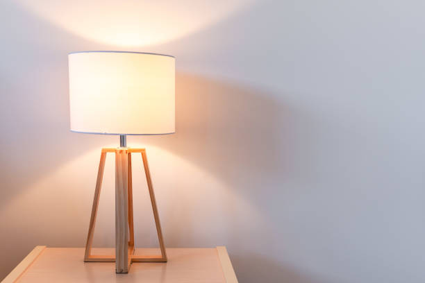 istock Modern bedroom lamp lit against white wall with copy space 980451228