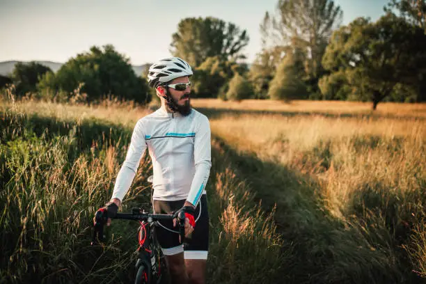 Young male athlete road cycling on a country road, taking a break