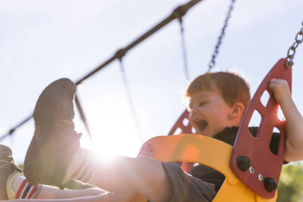 счастливый рыжий малыш мальчик сидит на детской площадке swing на открытом воздухе - child swing swinging balance стоковые фото и изображения